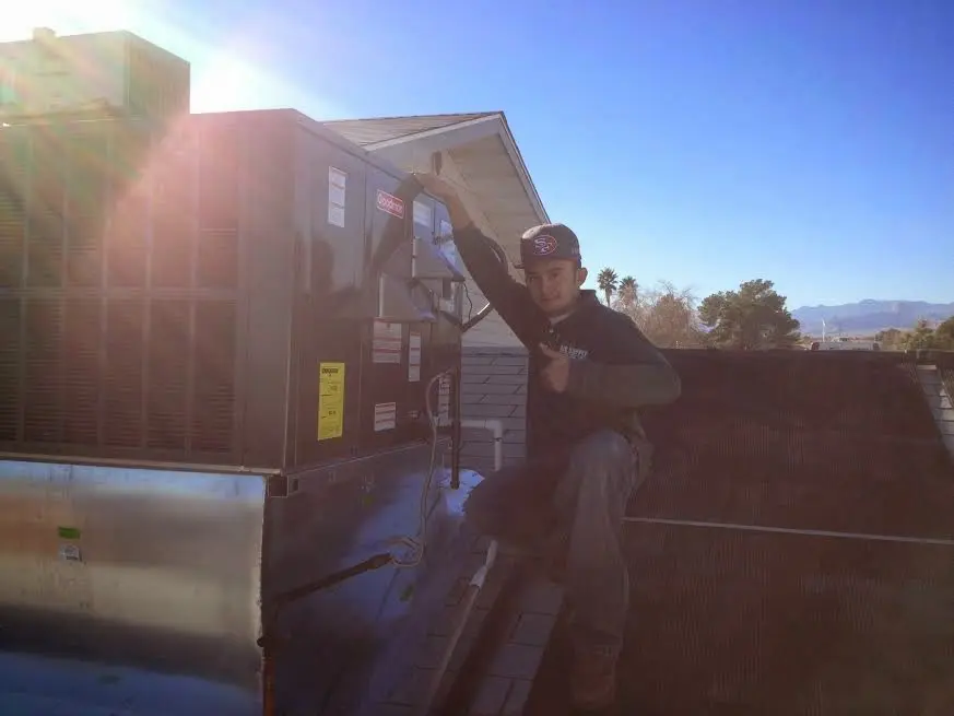 HVAC technician performing Heat Pump Repair on a rooftop unit in California City